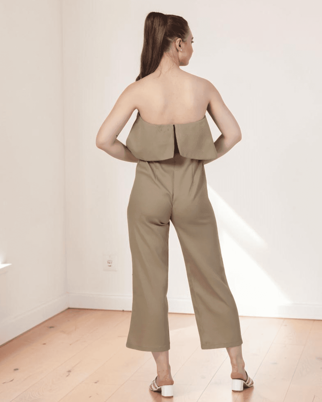 Back view of beige strapless jumpsuit with overlay and zipper closure