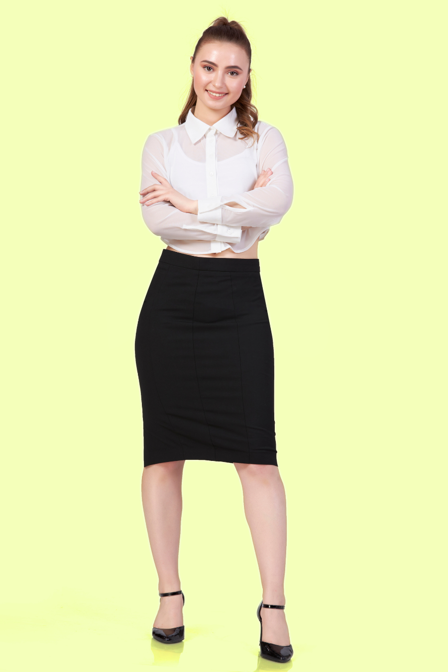 Full length image of a model wearing Cropped, long-sleeve shirt with a classic collar paired with a black midi skirt.