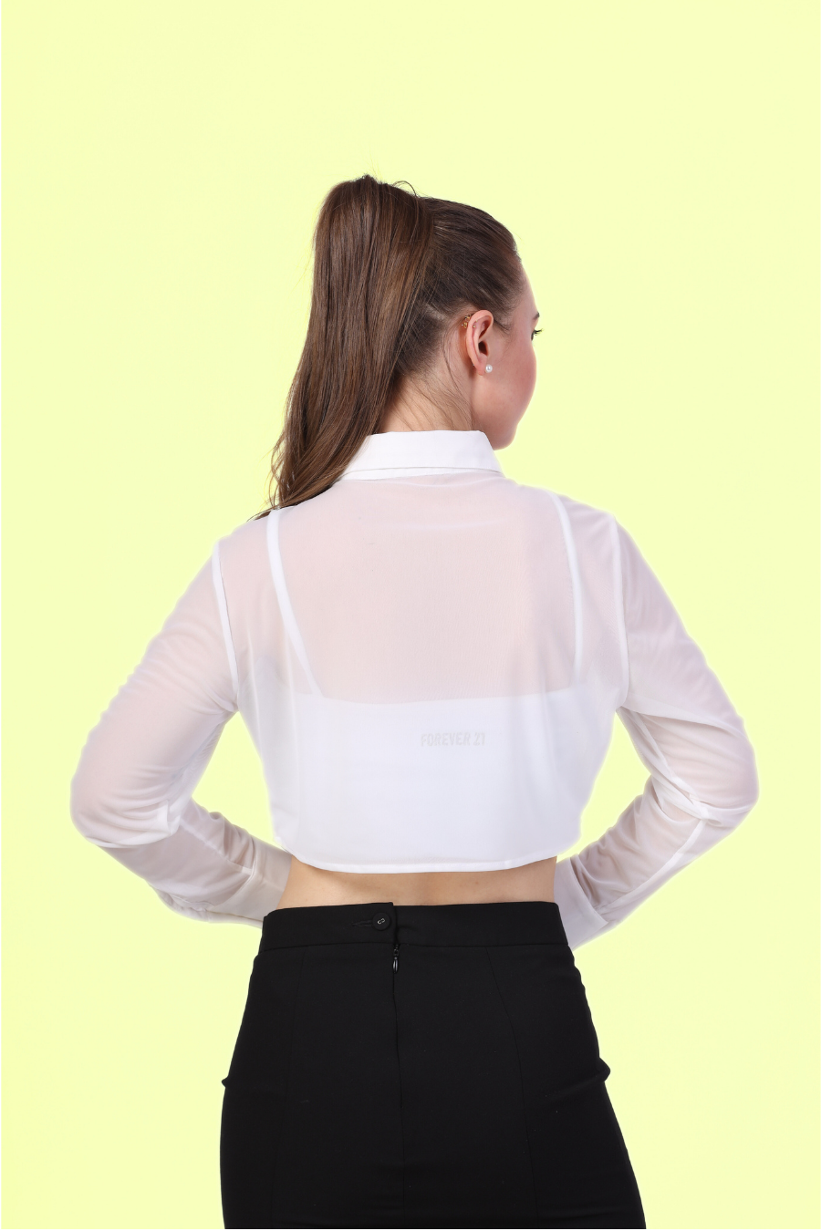 Back view of a model wearing Cropped, long-sleeve shirt with a classic collar paired with a black midi skirt