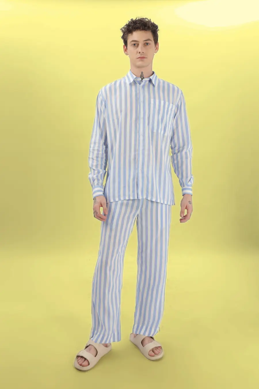 Another model showcasing the 'Arbor' men's pajama set sewing pattern. Striped cotton fabric with a button-up shirt and elastic-waist pants.