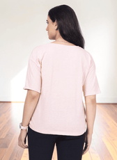 back view of woman in pink V-neck T-shirt, showing relaxed fit and short sleeves