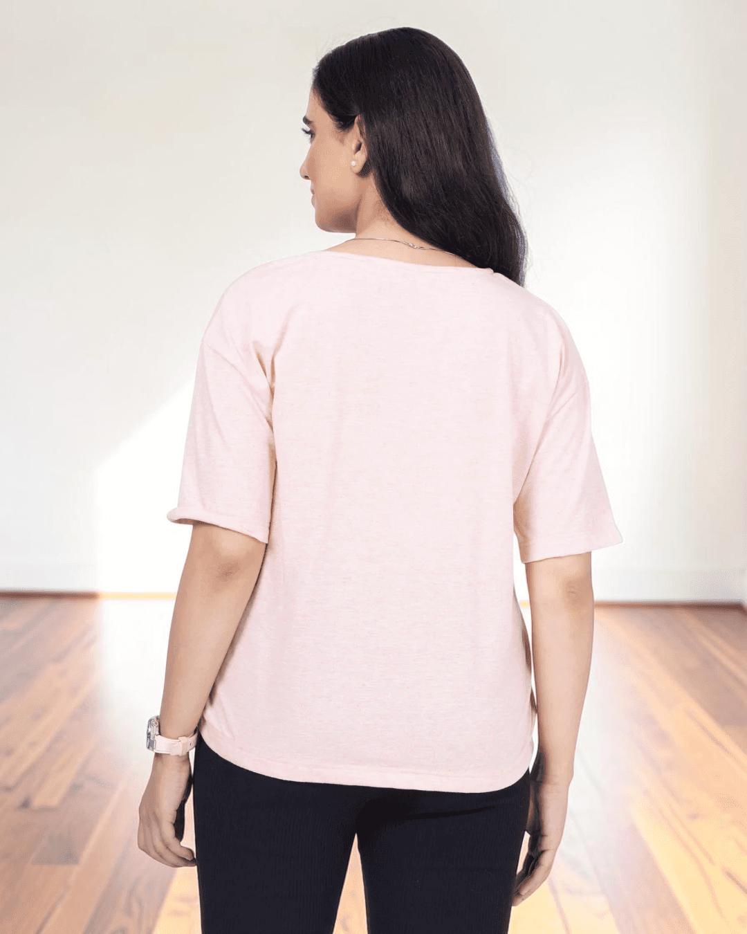 back view of woman in pink V-neck T-shirt, showing relaxed fit and short sleeves