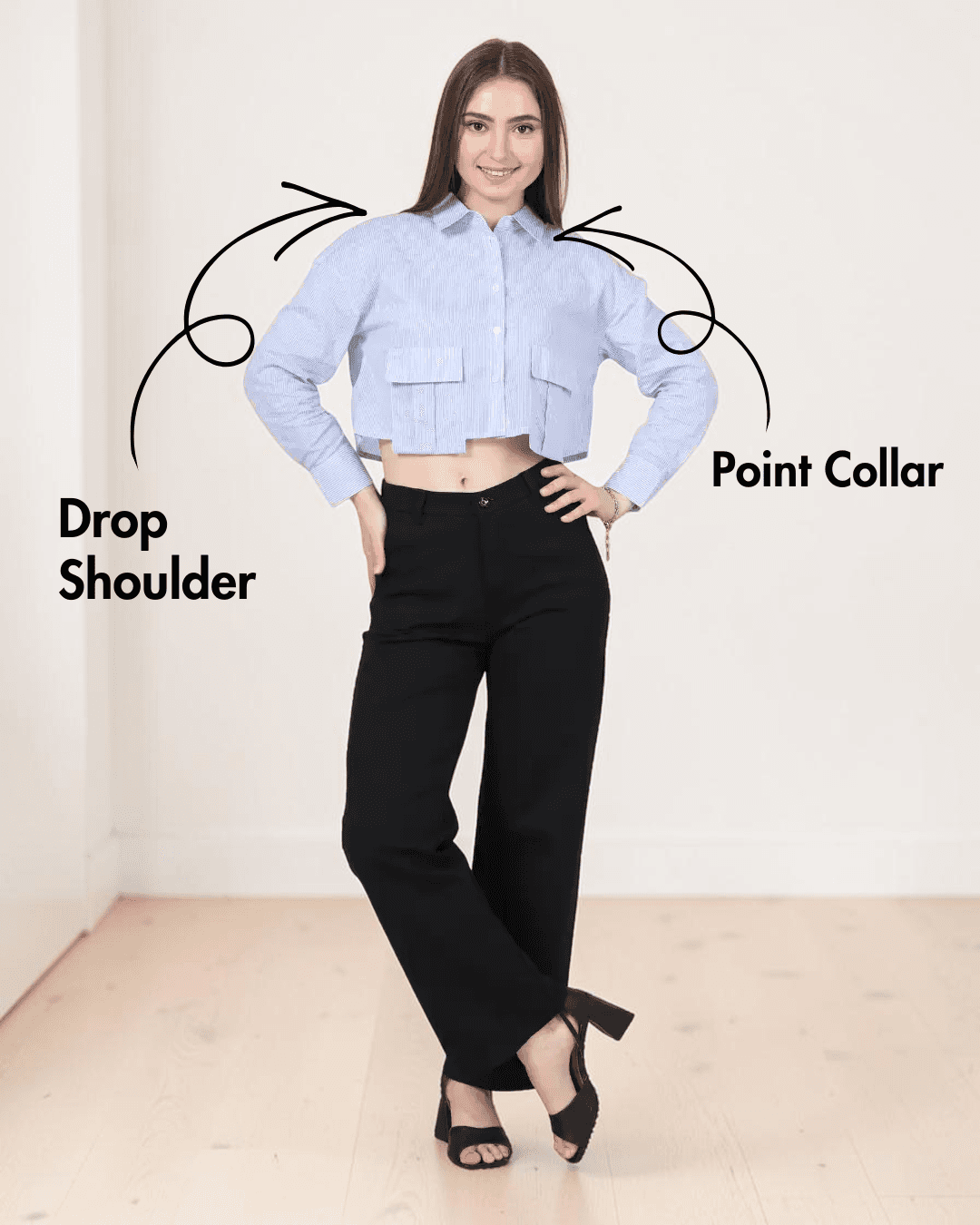 Model in cropped blue striped utility shirt with large bellows pockets, long sleeves, point collar, and black pants