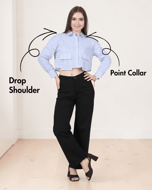 Model in cropped blue striped utility shirt with large bellows pockets, long sleeves, point collar, and black pants