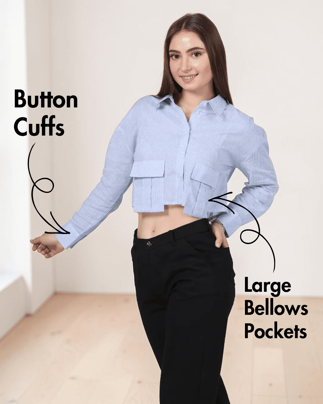 Closeup view of woman in blue striped utility shirt with point collar and long sleeves, paired with black pants