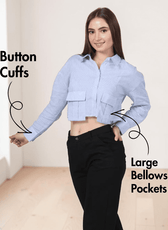 Closeup view of woman in blue striped utility shirt with point collar and long sleeves, paired with black pants