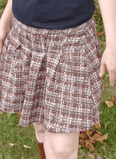 Model wearing a plaid pleated mini skirt with high waist and pleats, styled with casual sneakers