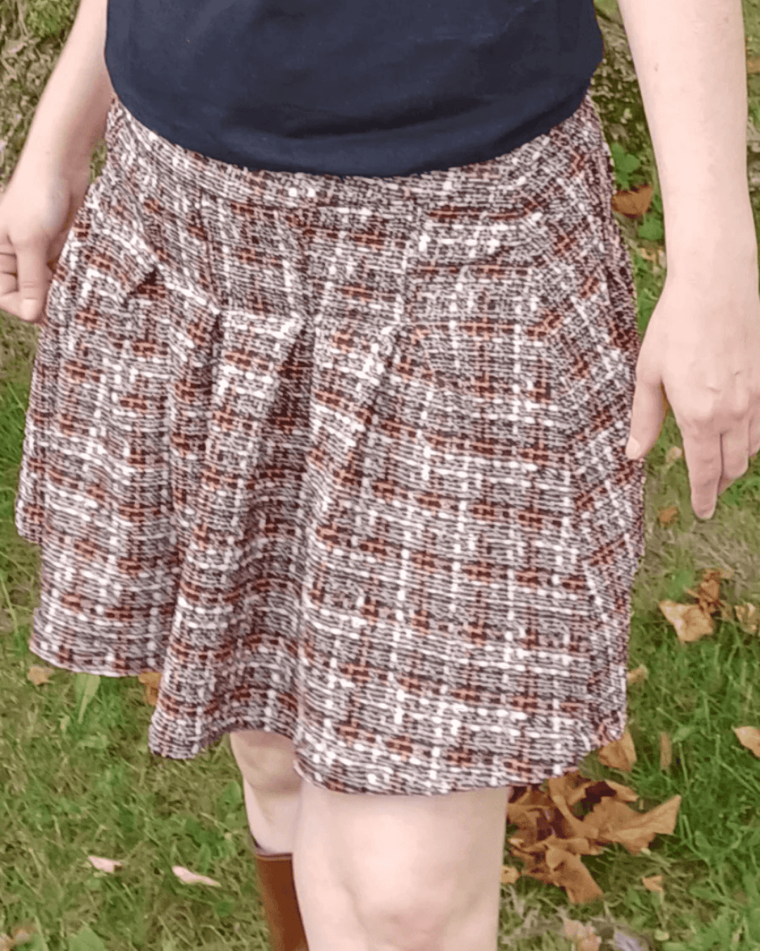 Model wearing a plaid pleated mini skirt with high waist and pleats, styled with casual sneakers