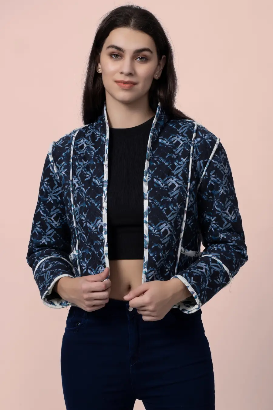 Model adjusting the Romy reversible quilted jacket in a dark blue geometric pattern. A stylish, lightweight outerwear piece with contrast binding.