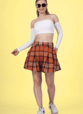 Woman wearing a box pleat skirt with a white off-shoulder top and sneakers