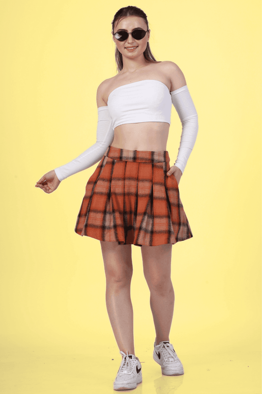 Woman wearing a box pleat skirt with a white off-shoulder top and sneakers