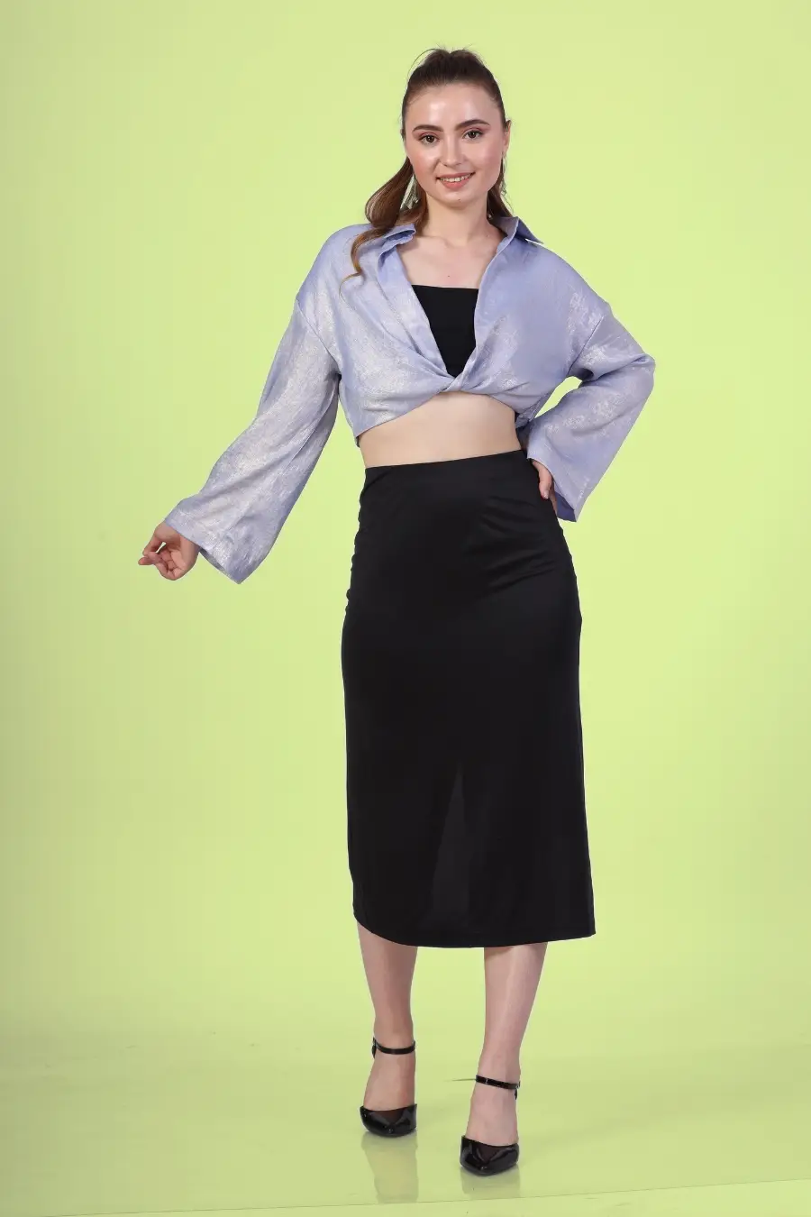 Front view of a model wearing a twist front shirt with full length sleeves and black skirt