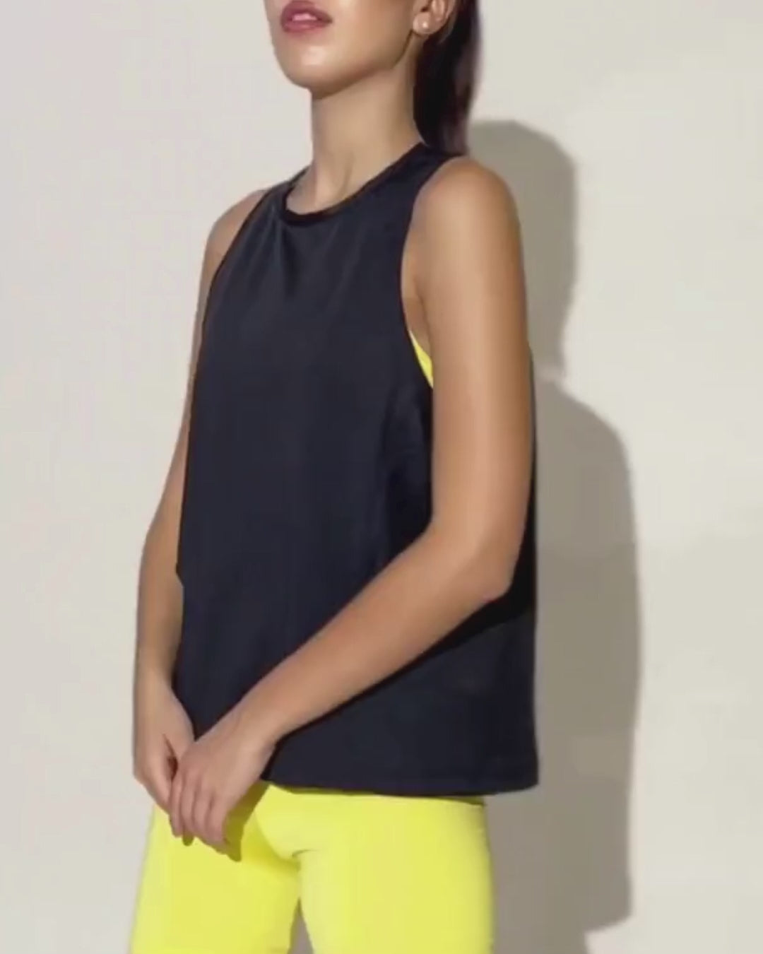 Model wearing black sleeveless athletic tank top with yellow shorts