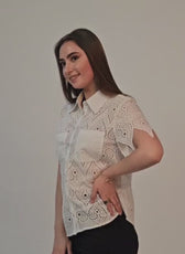 Woman wearing a white lace short sleeve shirt with button front, standing sideways, smiling