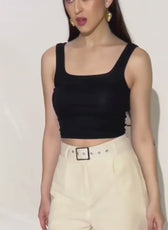 Model wearing black crop top and high waisted beige shorts, fashion styling