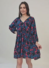 Woman modeling a boho dress with floral print, V-neck, long sleeves, and relaxed fit, showcasing the sewing pattern's style