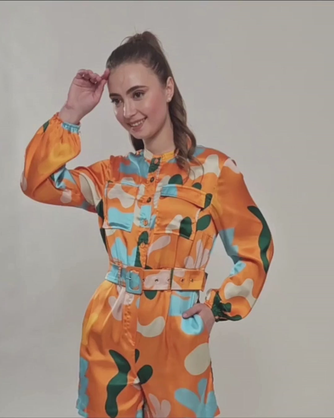 Model wearing vibrant printed jumpsuit with belt