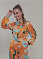 Model wearing vibrant printed jumpsuit with belt