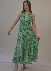 Model twirling in a green halter neck maxi dress, highlighting the flowy tiered skirt. Sewing pattern available as a digital download for DIY fashion.