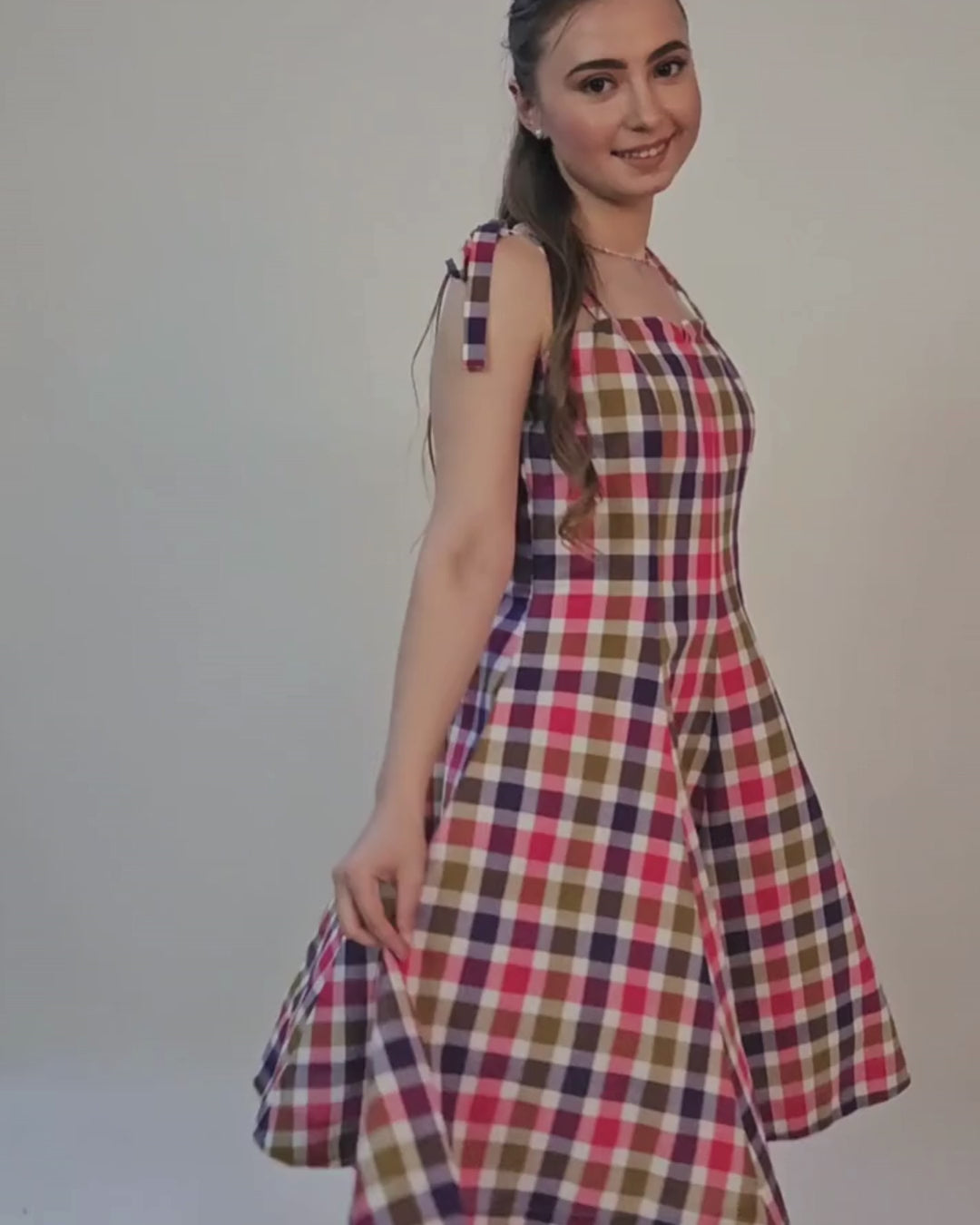 Model wearing a plaid dress with tie straps, showcasing the finished garment from the sewing pattern