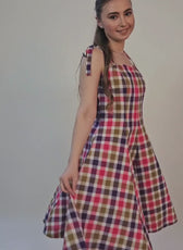 Model wearing a plaid dress with tie straps, showcasing the finished garment from the sewing pattern
