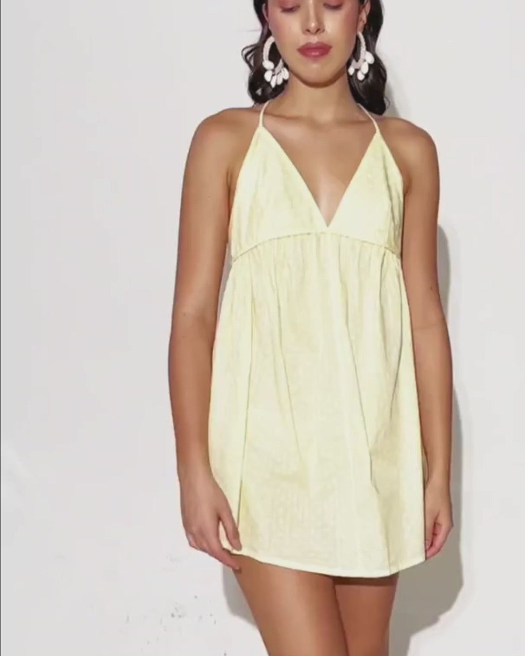 Model wearing yellow halter beach dress with plunging neckline, showing fit and style