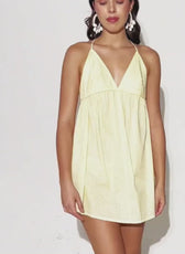 Model wearing yellow halter beach dress with plunging neckline, showing fit and style