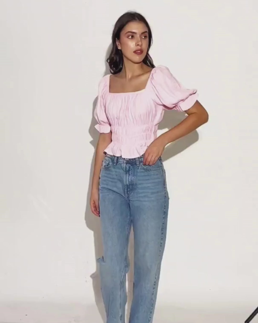 Model wearing pink puff-sleeve blouse with high-waisted jeans, showcasing the Milkmaid Top 'Samara'