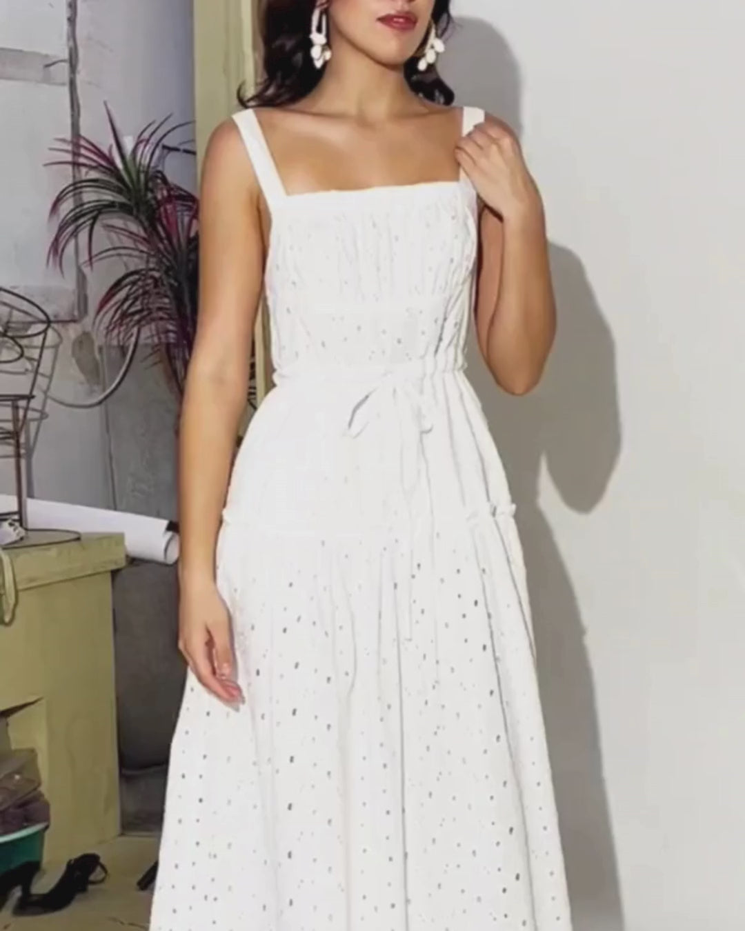 Model wearing a white sundress with a fitted bodice, tiered skirt, and adjustable straps, showcasing the dress design