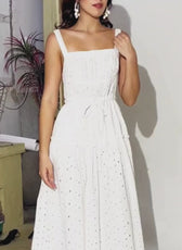Model wearing a white sundress with a fitted bodice, tiered skirt, and adjustable straps, showcasing the dress design