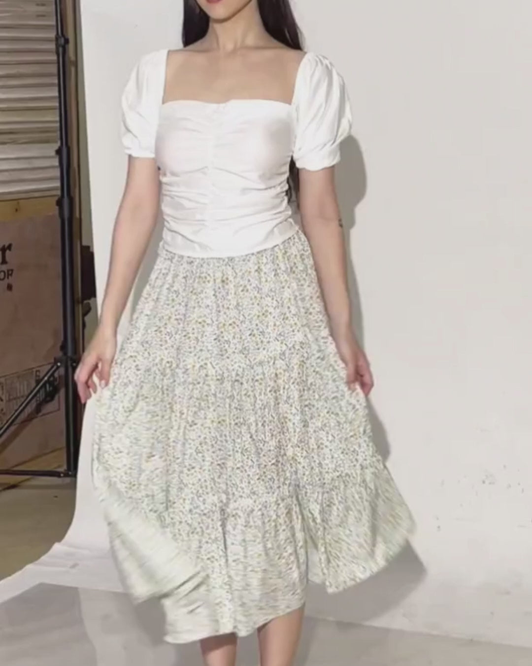 Photo of woman wearing a white puff sleeve top and a tiered midi skirt
