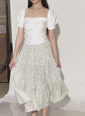Photo of woman wearing a white puff sleeve top and a tiered midi skirt