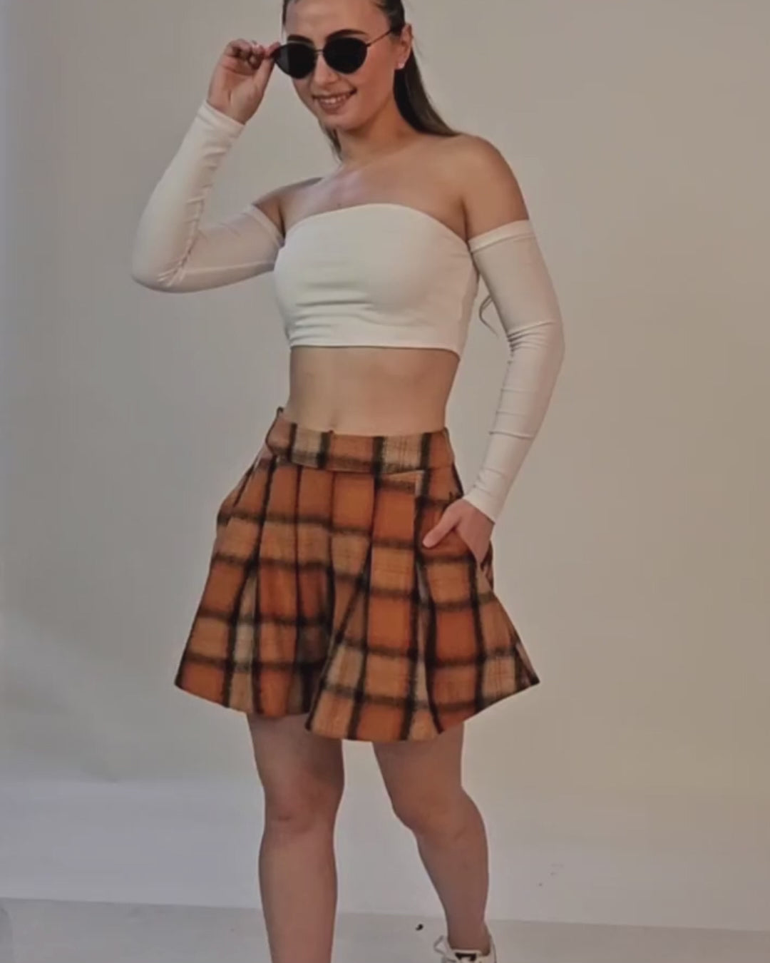 Model wearing off-shoulder crop top and plaid shorts, showcasing trendy fashion style