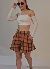 Model wearing off-shoulder crop top and plaid shorts, showcasing trendy fashion style