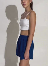 Model wearing white crop top and blue shorts, demonstrating athletic shorts style