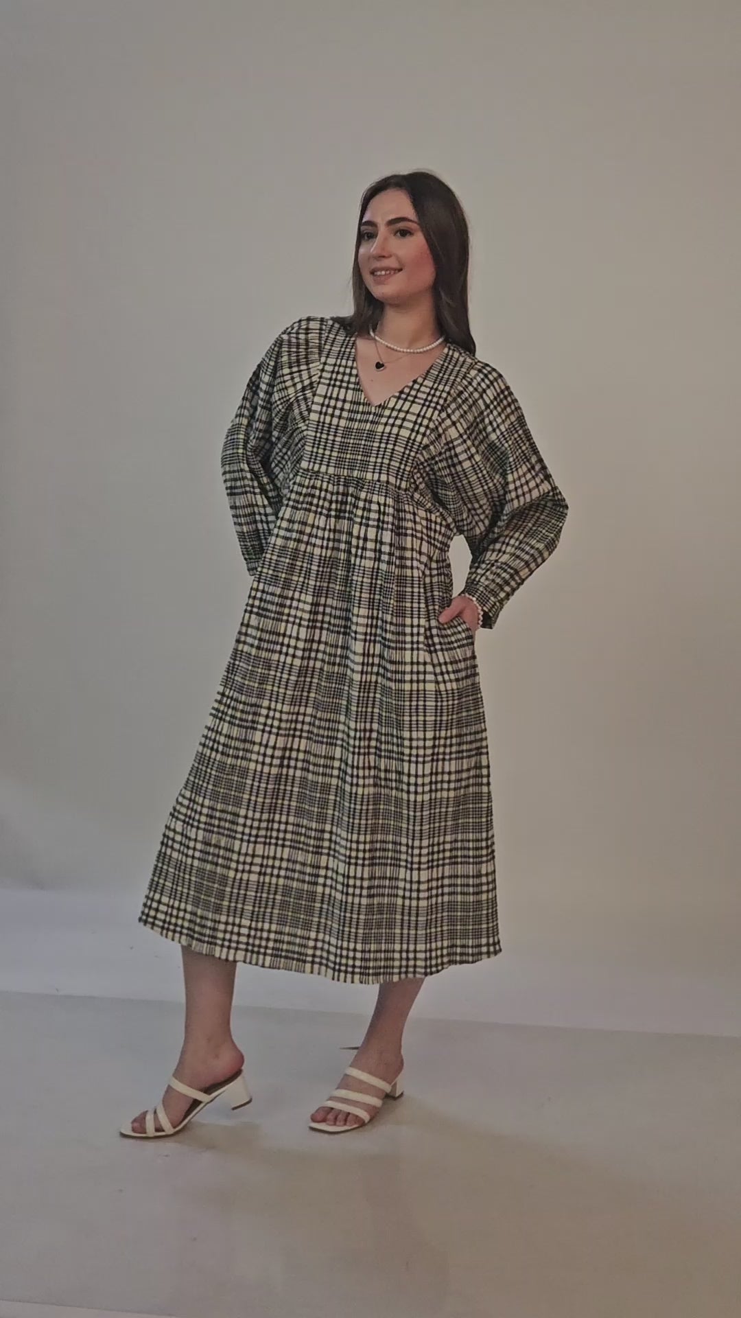 Video of a model posing in a long sleeves midi dress sewed with WInslet's patterns