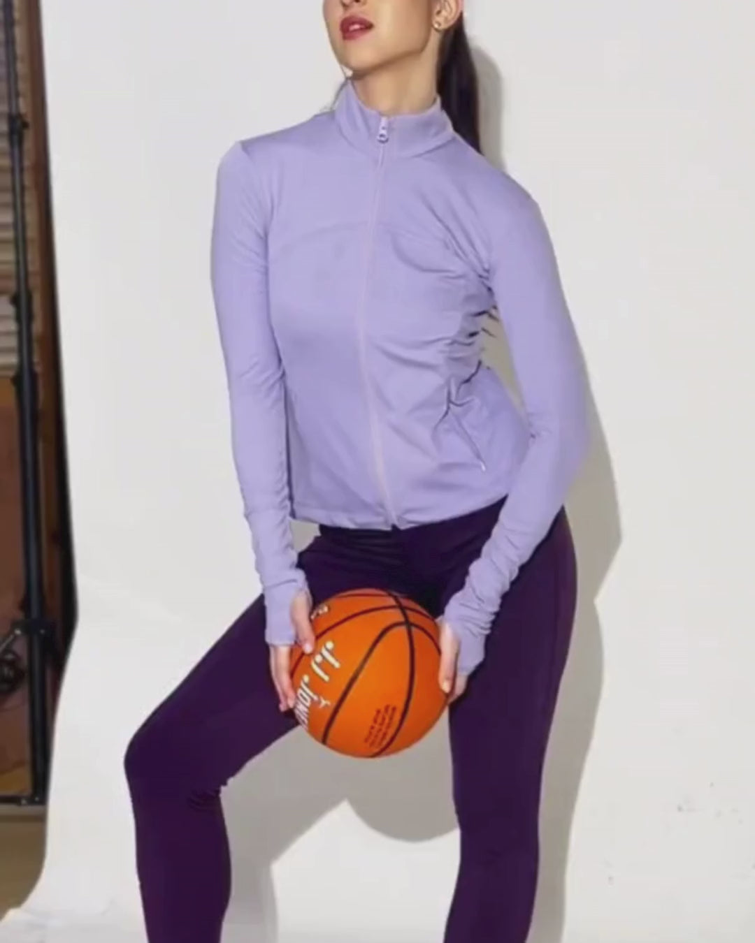 Model wearing lavender sports jacket with high collar, full zip, and activewear style