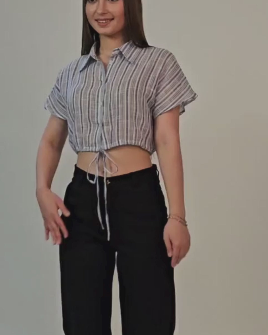 Woman wearing a cropped shirt with drawstring hem, styled with black pants