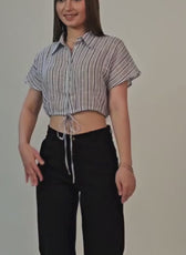 Woman wearing a cropped shirt with drawstring hem, styled with black pants