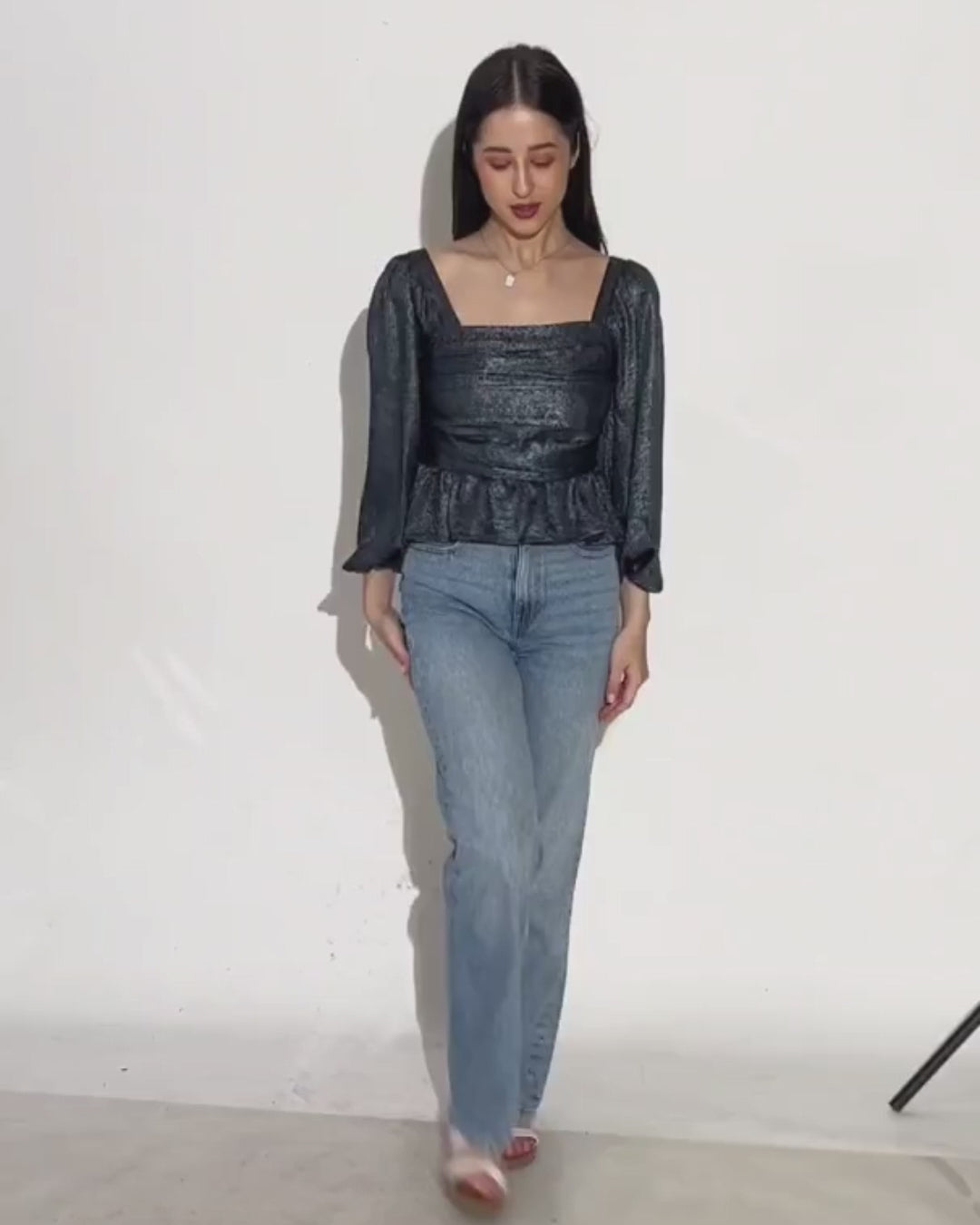 Women's black peplum top with square neckline and long puff sleeves, paired with light blue jeans