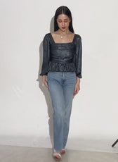 Women's black peplum top with square neckline and long puff sleeves, paired with light blue jeans
