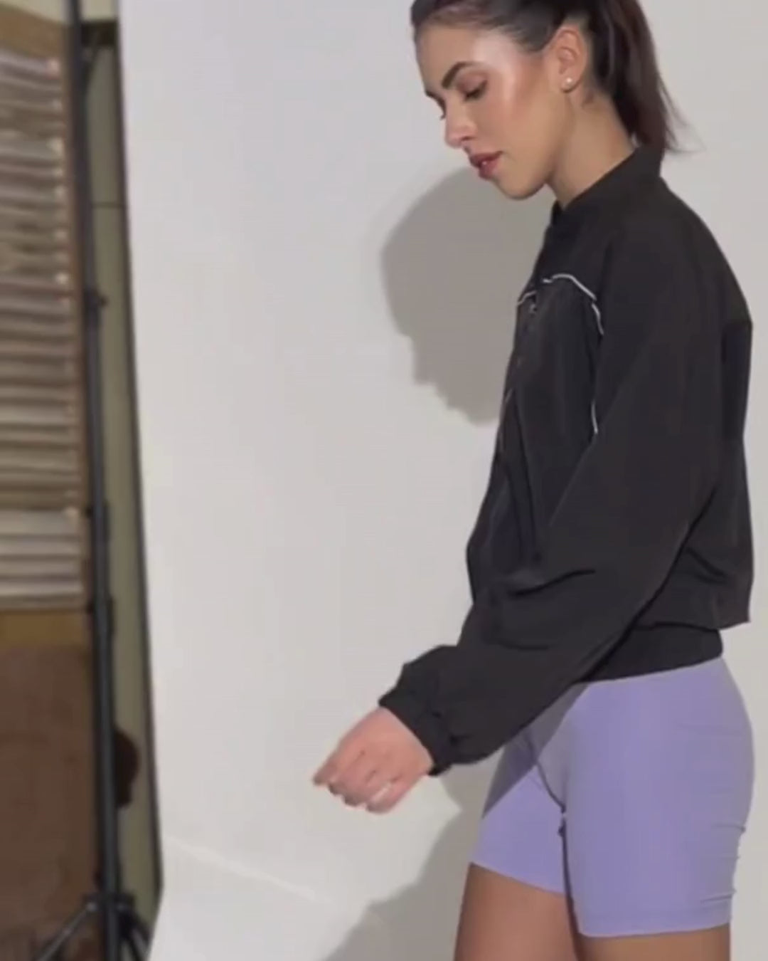 Woman wearing black windbreaker jacket with purple shorts, demonstrating the Naomi windbreaker style