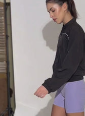 Woman wearing black windbreaker jacket with purple shorts, demonstrating the Naomi windbreaker style