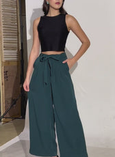 Behind-the-scenes shot of a model wearing wide-leg belted trousers. Showcases the elegant drape and structured fit of the design.