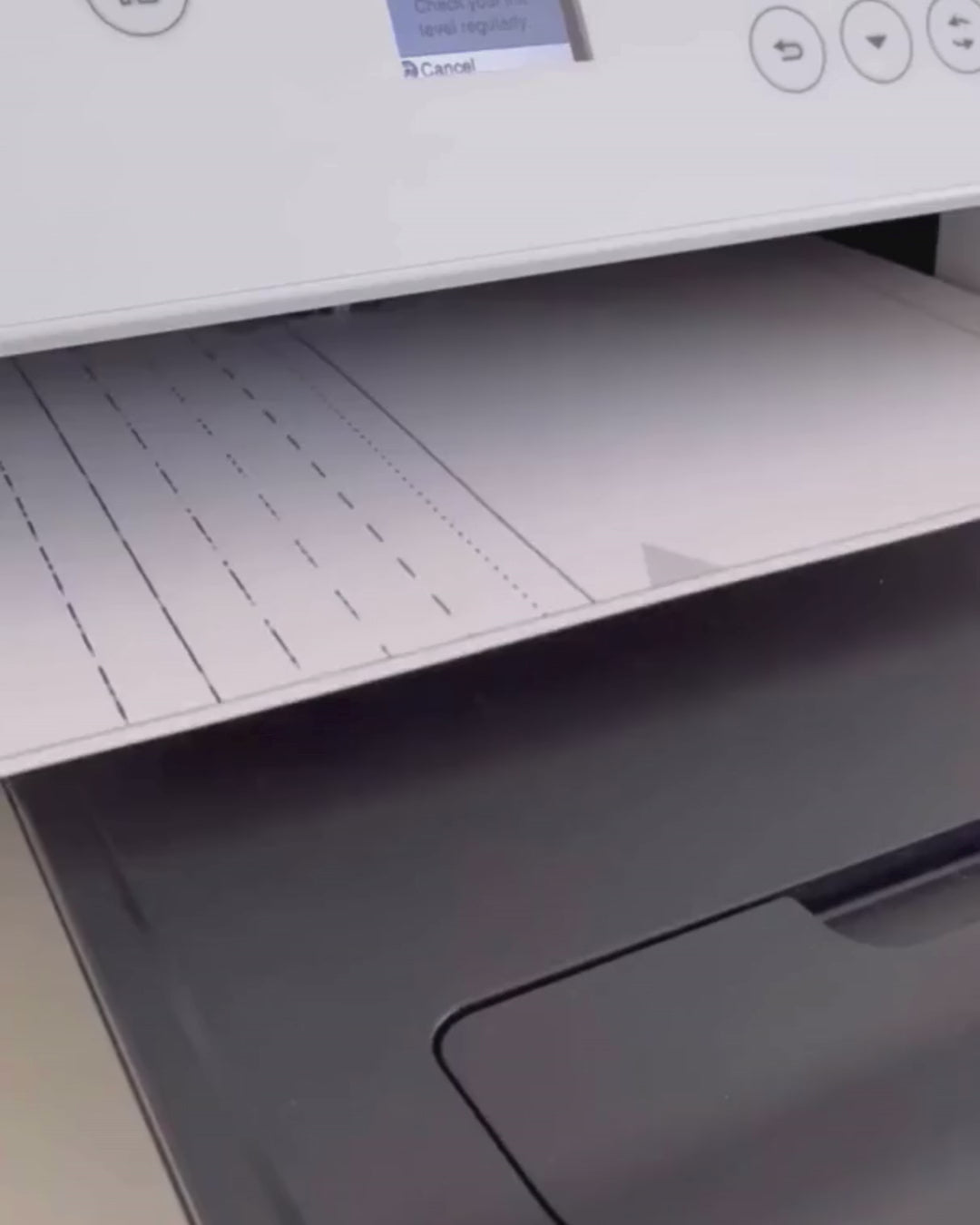 Printer with paper tray open, showing printing paper and a printed pattern or document