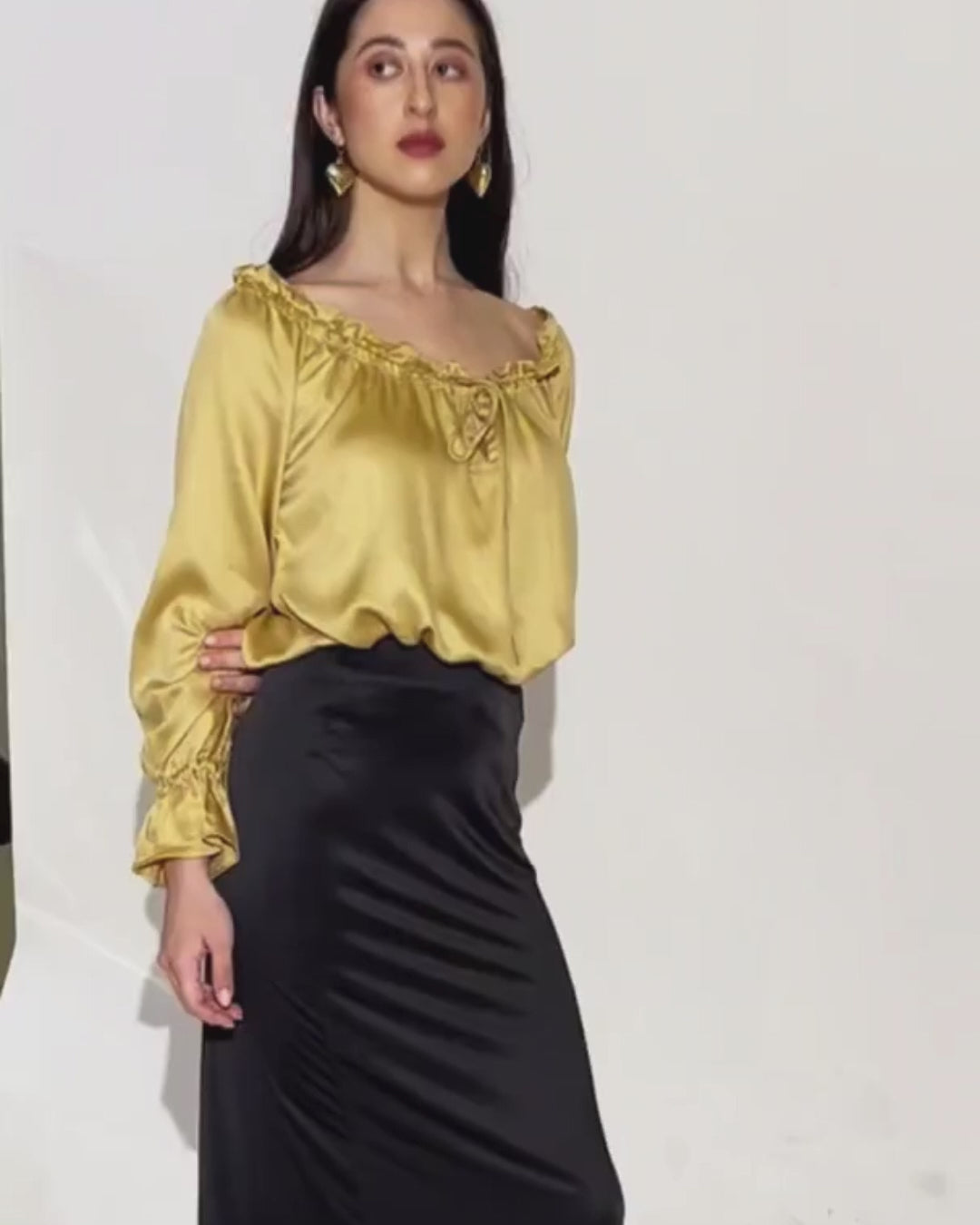 Woman wearing yellow satin peasant blouse with ruffled neckline and long sleeves