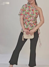 Photo of woman wearing floral one shoulder kimono top with side tie, paired with black pants and small handbag
